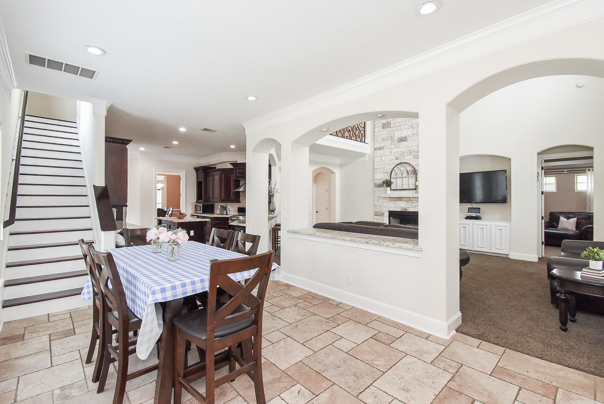633 Crenshaw Road Houston, TX 77504 - Photo 46 of 46 This inviting home features an open floor plan with a cozy dining area, tile flooring, and a view into a spacious living room with a fireplace. The kitchen boasts dark cabinetry and modern appliances, while an elegant staircase leads to the upper level.