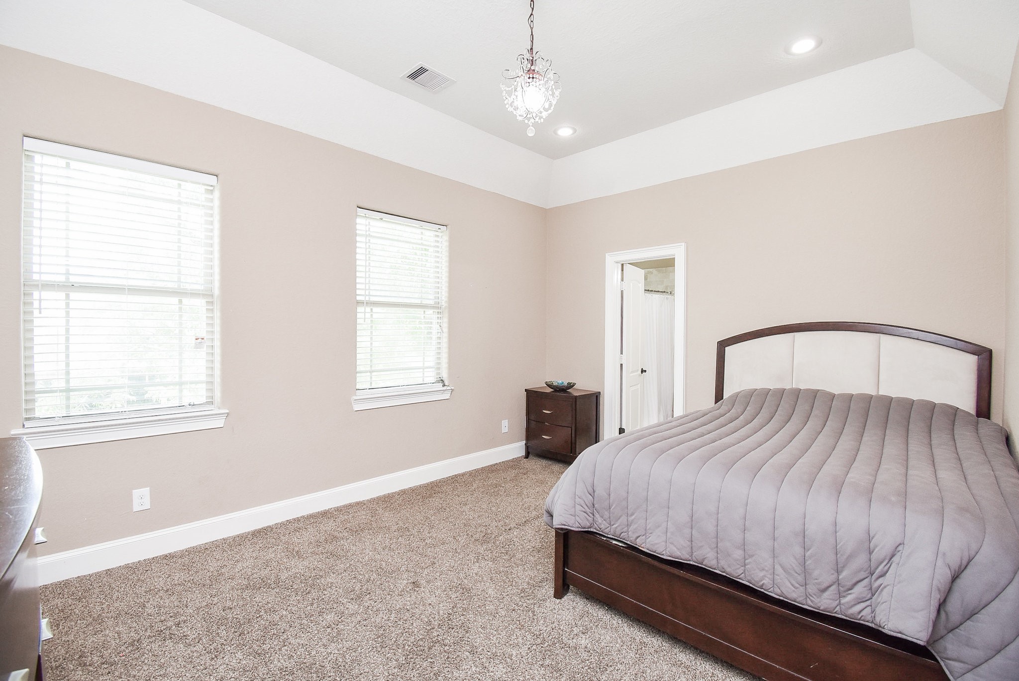 633 Crenshaw Road Houston, TX 77504 - Photo 30 of 46 This spacious bedroom features a neutral color palette with two large windows for natural light, a plush carpet, and a cozy bed. The room includes a small dresser and has an en-suite bathroom, offering a comfortable and private retreat.
