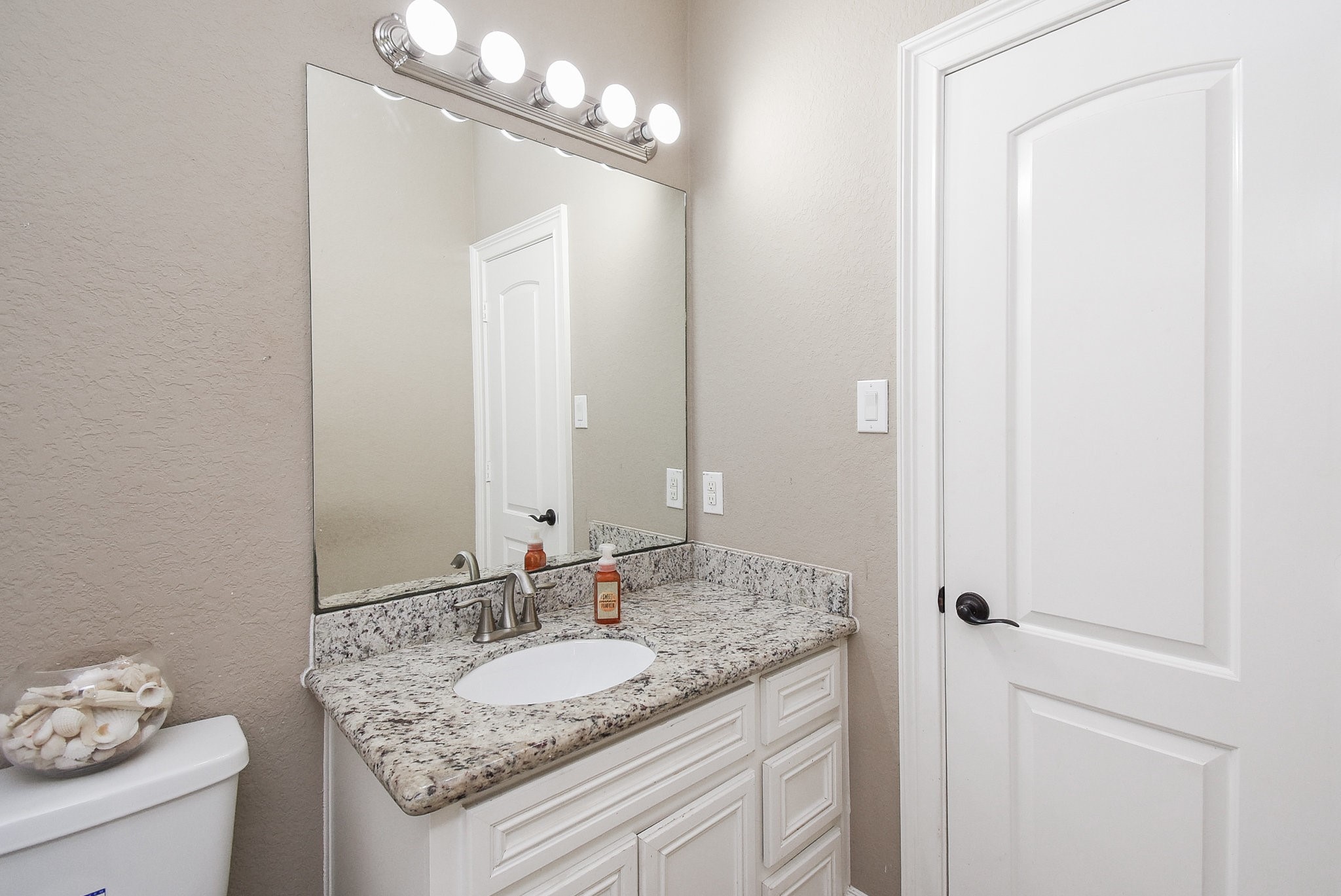 633 Crenshaw Road Houston, TX 77504 - Photo 37 of 46 This bathroom features a sleek design with a granite countertop, a large mirror, and modern lighting above. The neutral color palette and white cabinetry create a clean, inviting space.