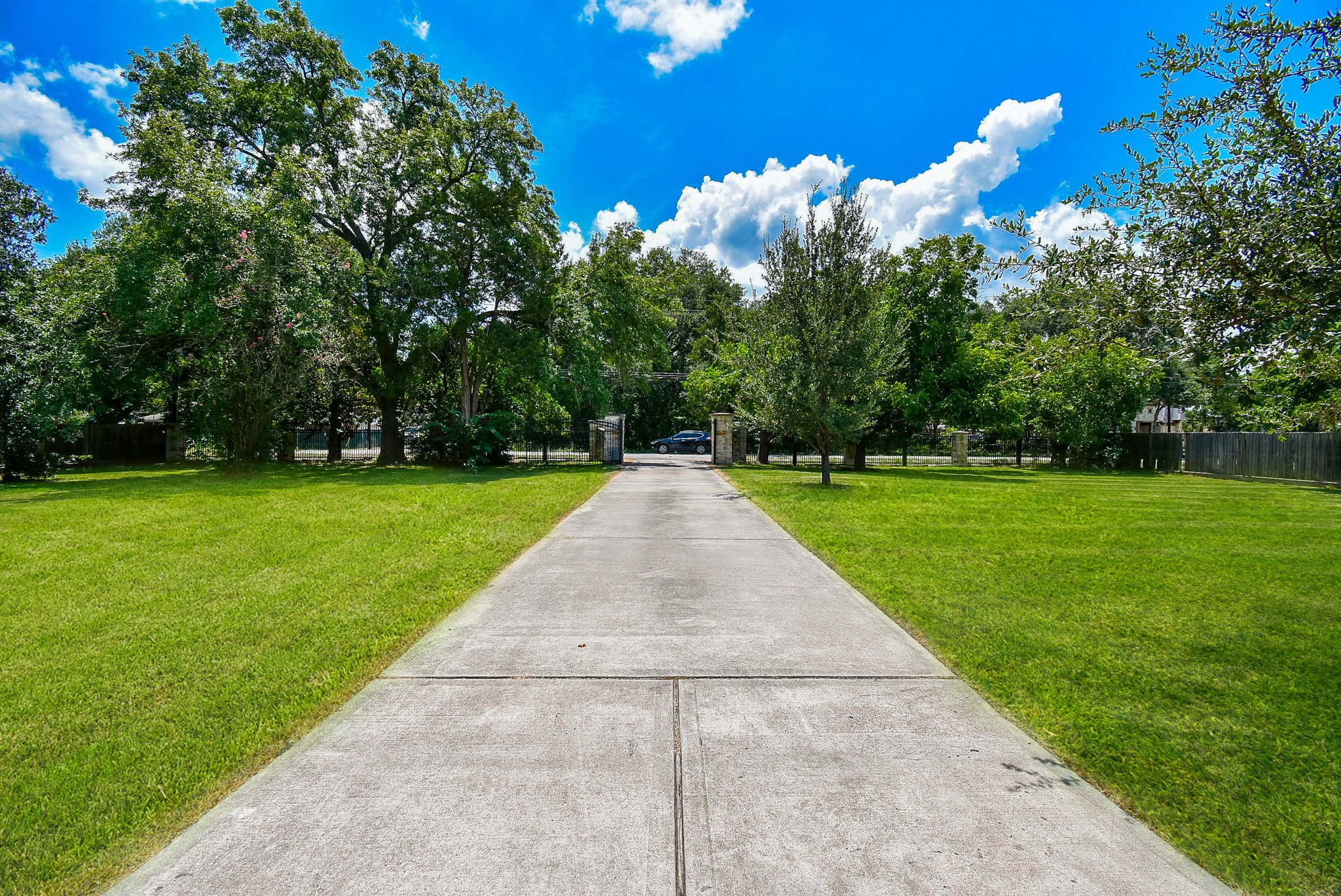 633 Crenshaw Road Houston, TX 77504 - Photo 42 of 46 A long, inviting driveway leads through a spacious, lush green lawn with mature trees on either side, providing a serene and private entrance to the property.