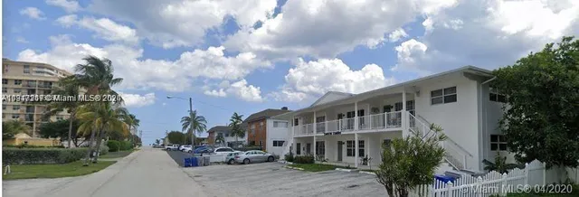 a backyard of a house with table and chairs plants and large tree