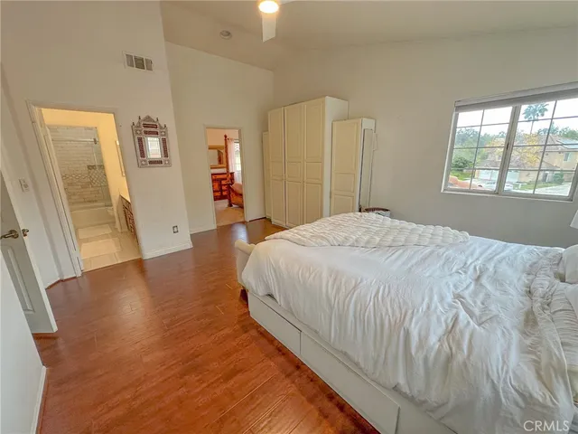 a spacious bedroom with a bed and a wooden floor