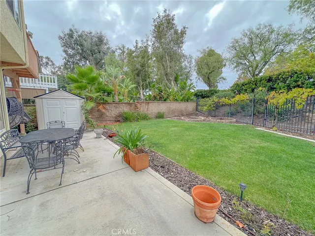 a view of a backyard with table and chairs potted plants and tree