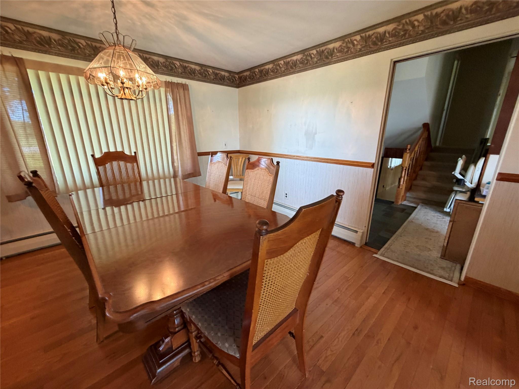 8886 East Burnside Road Brown City, MI 48416 - Photo 12 of 22 Dining area featuring wood-finish flooring, a decorative chandelier, and wainscoting with a wooden rail