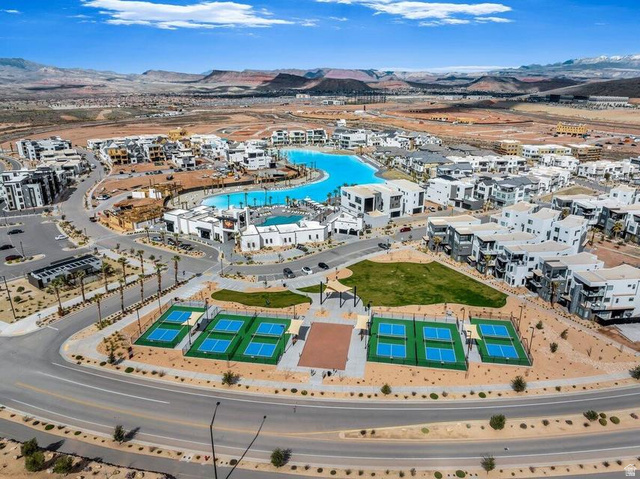 5898 Jasper Rdg Drive St. George, UT 84790 - Photo 28 of 41 Aerial view of a resort-style community featuring a striking lagoon-shaped saltwater pool with lounging areas, professional-grade tennis courts, manicured landscaping with native desert plantings, and contemporary white residential architecture throughout