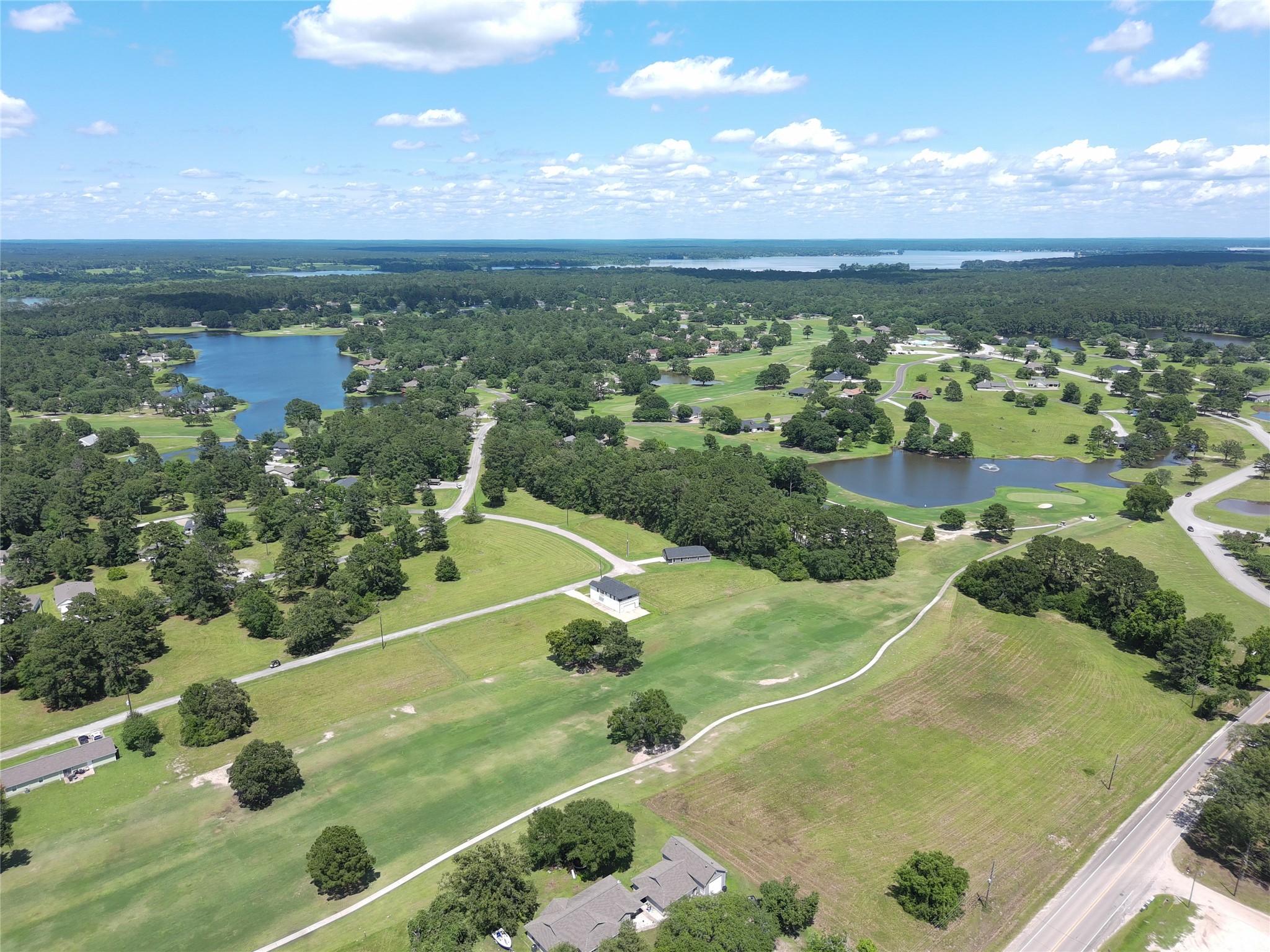59 Oakridge South Trinity, TX 75862 - Photo 3 of 10 This aerial view showcases a serene, expansive landscape with lush greenery, multiple small lakes, and scattered homes. The area appears spacious and tranquil, ideal for those seeking a peaceful environment with natural beauty.