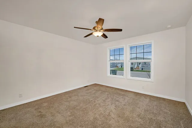 a view of an empty room with window and ceiling fan