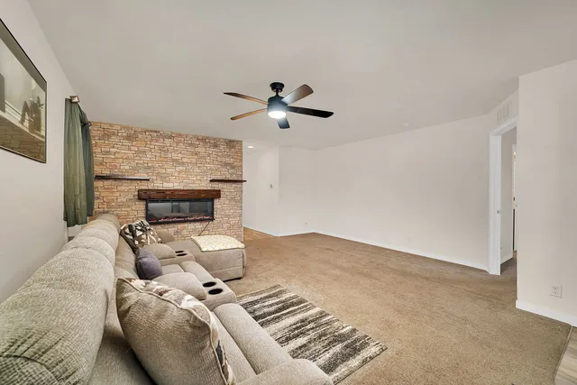 a living room with furniture a fireplace and a ceiling fan