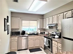 a kitchen with white cabinets white appliances a sink and a window