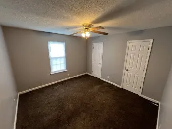 an empty room with windows and fan