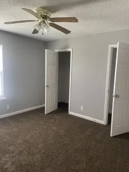 an empty room with closet and a ceiling fan