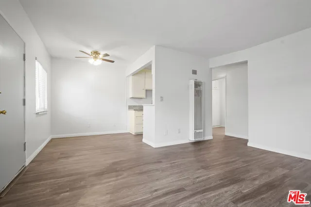 a view of empty room with wooden floor and ceiling fan