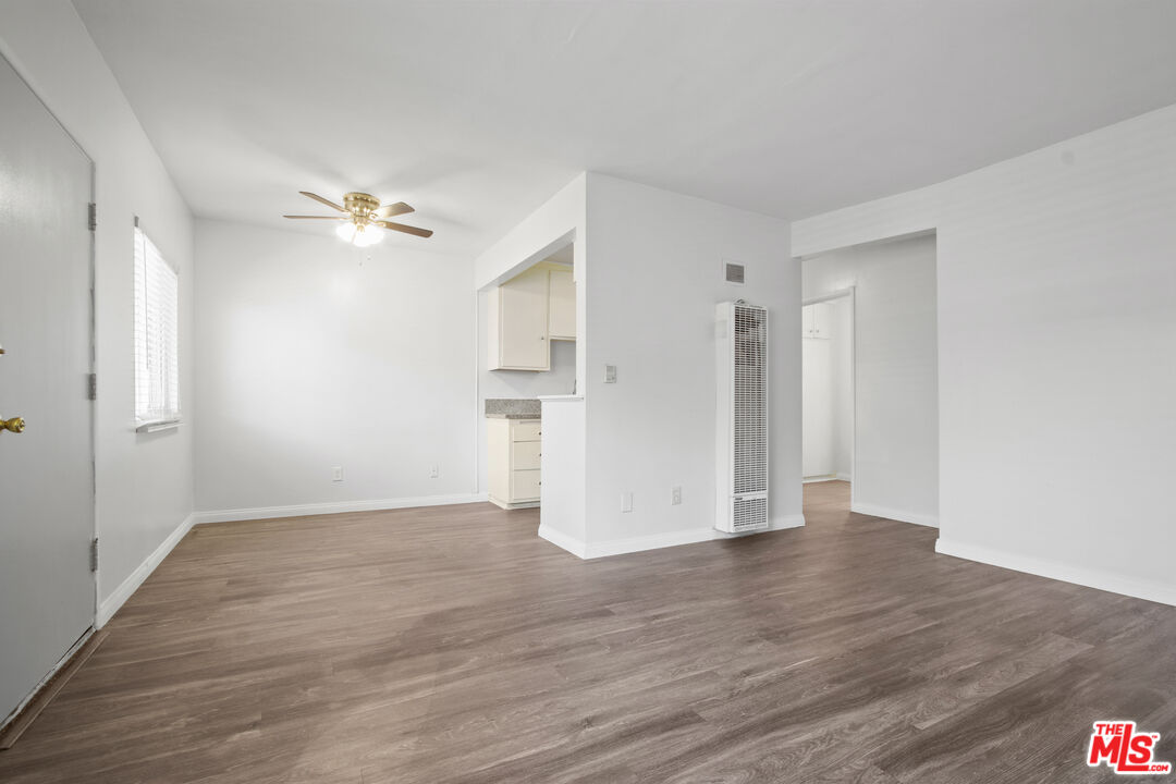 a view of empty room with wooden floor and ceiling fan