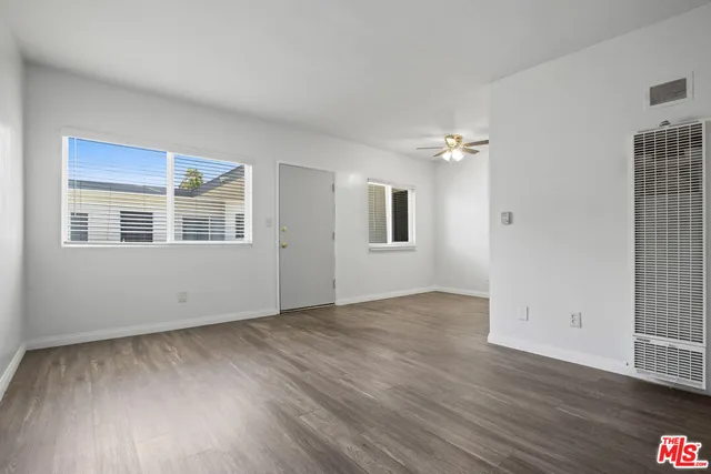 an empty room with wooden floor cabinet and windows