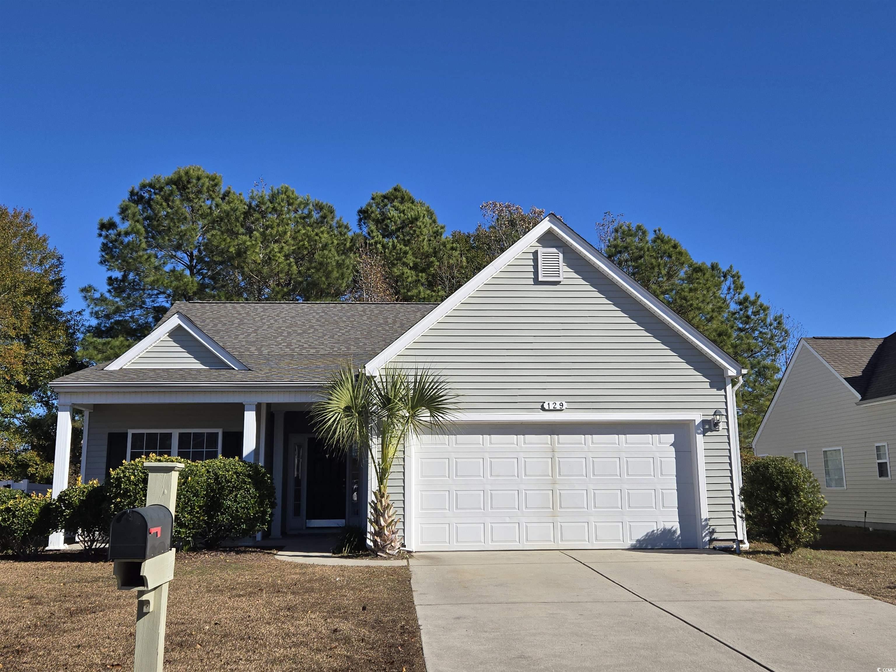 Ranch-style home with driveway, a porch, an attached garage, a shingled roof, and a front yard
