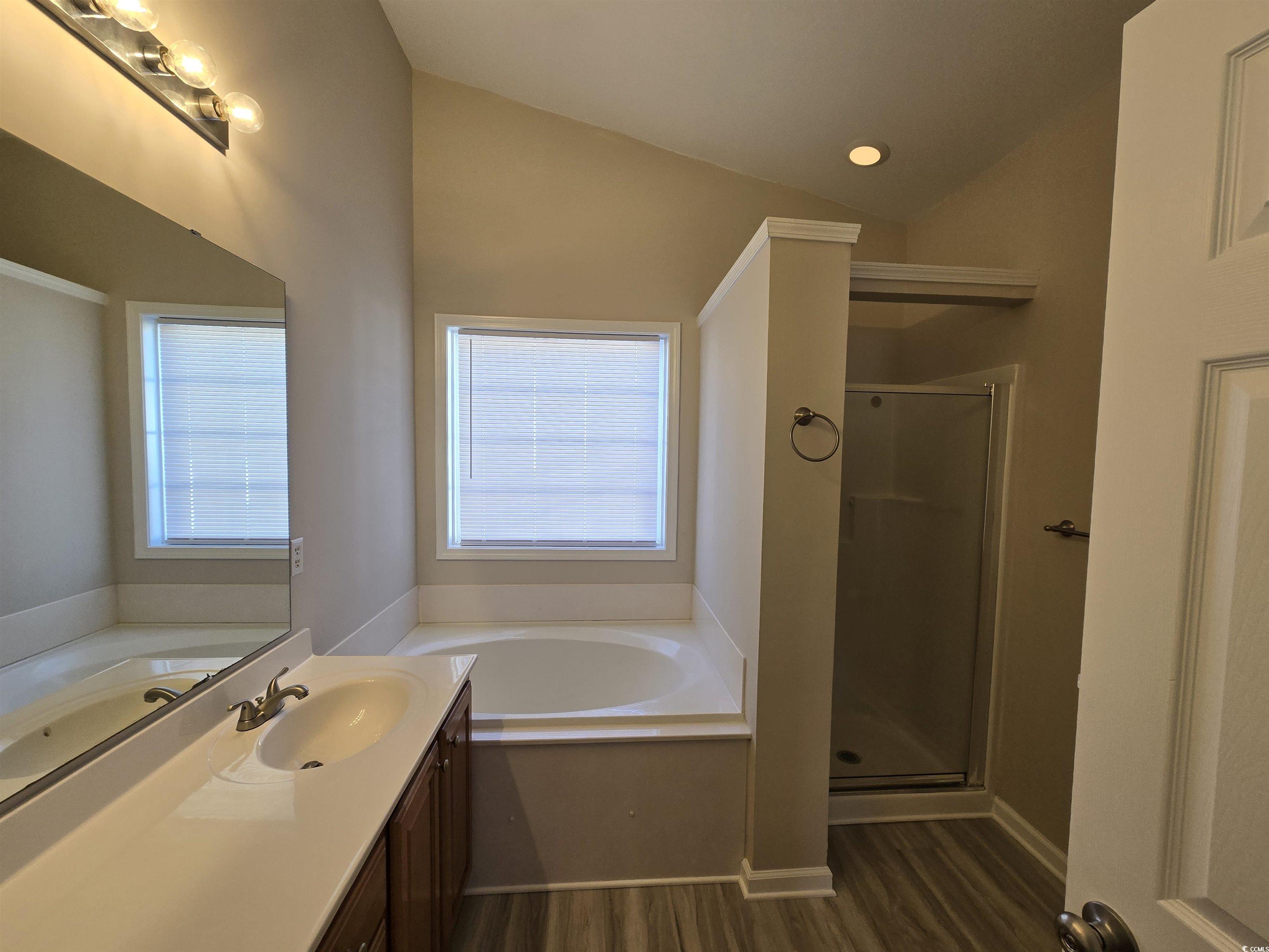129 Powder Springs Loop Myrtle Beach, SC 29588 - Photo 10 of 23 Full bathroom featuring vanity, a garden tub, a shower stall, dark wood-type flooring, and vaulted ceiling