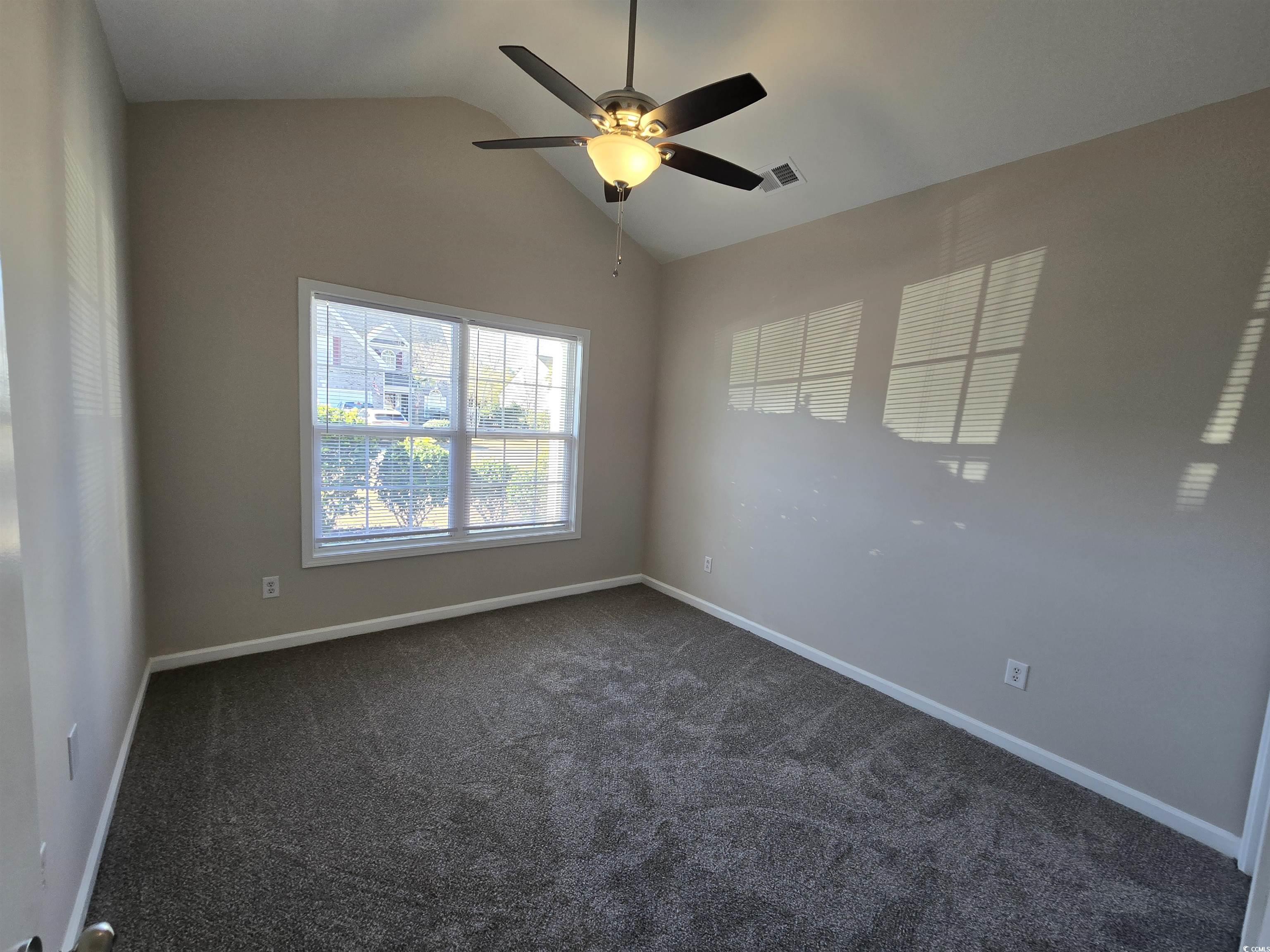 129 Powder Springs Loop Myrtle Beach, SC 29588 - Photo 13 of 23 Unfurnished room with lofted ceiling, ceiling fan, and dark carpet