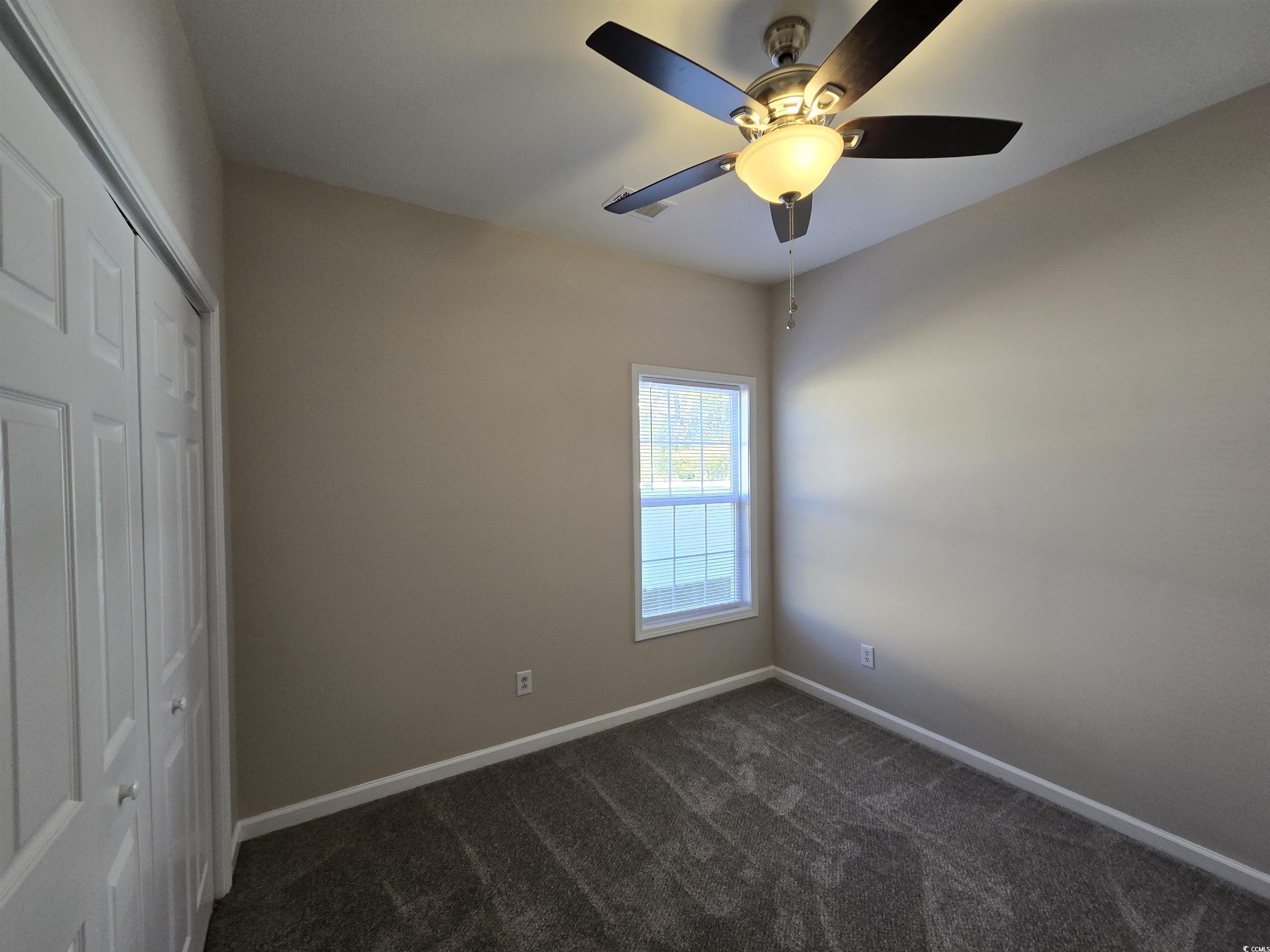 129 Powder Springs Loop Myrtle Beach, SC 29588 - Photo 15 of 23 Unfurnished bedroom with a closet, a ceiling fan, and dark colored carpet