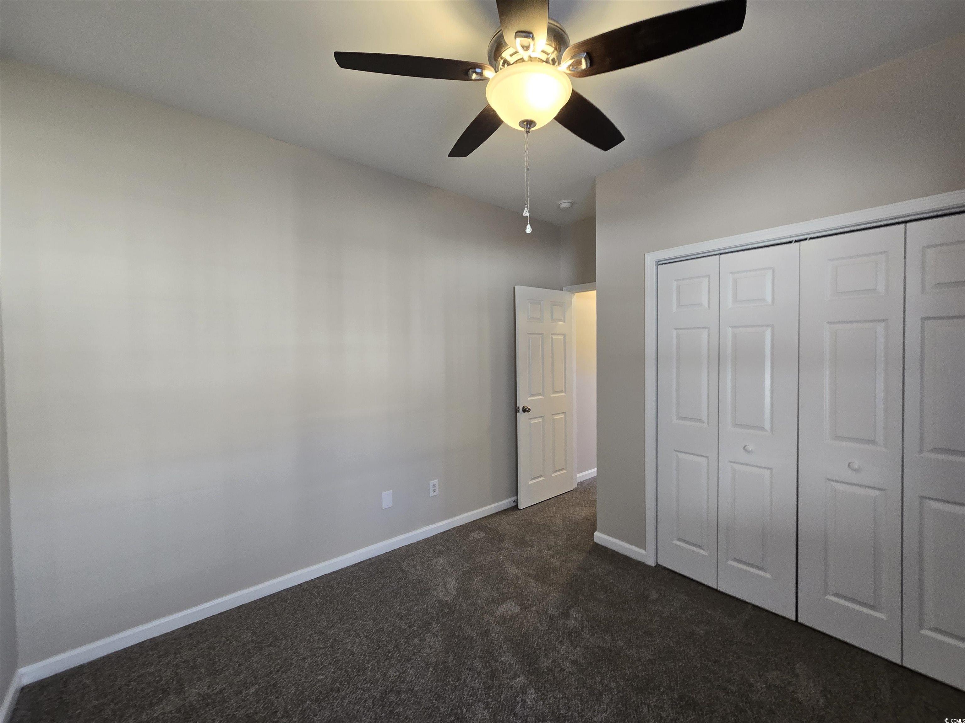 129 Powder Springs Loop Myrtle Beach, SC 29588 - Photo 16 of 23 Unfurnished bedroom featuring ceiling fan, dark colored carpet, and a closet