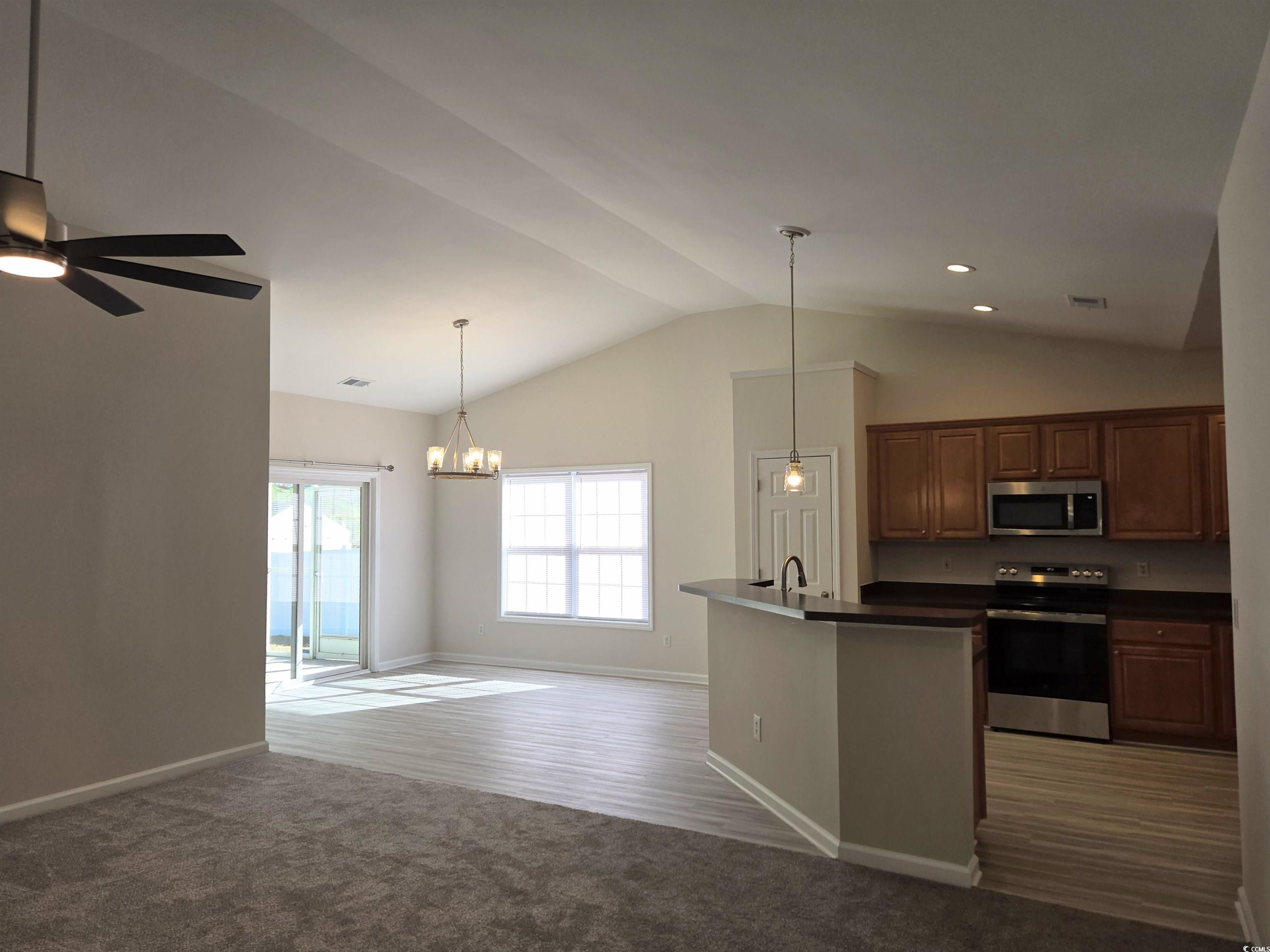 129 Powder Springs Loop Myrtle Beach, SC 29588 - Photo 23 of 23 Kitchen with dark countertops, appliances with stainless steel finishes, decorative light fixtures, open floor plan, and dark colored carpet