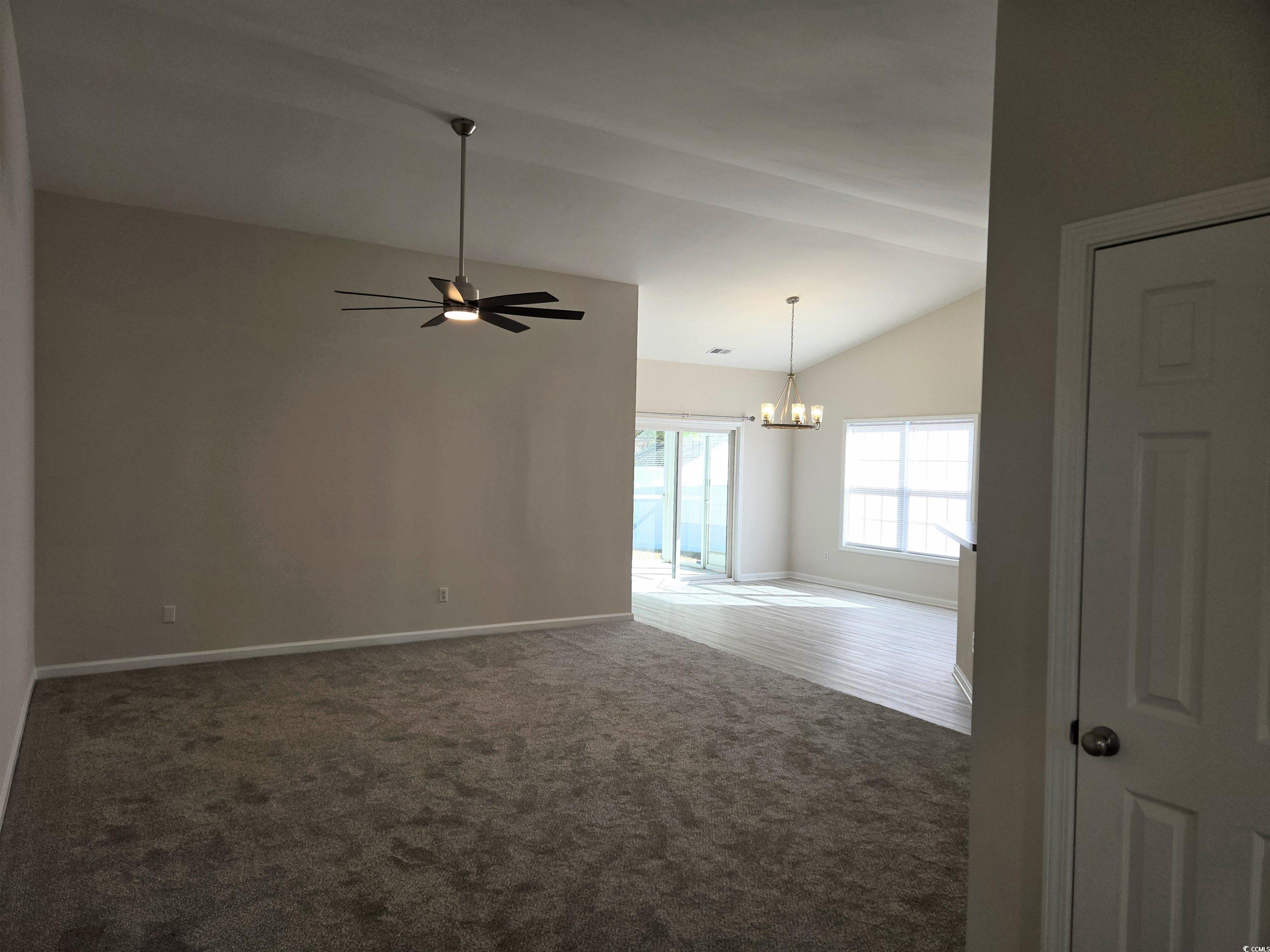129 Powder Springs Loop Myrtle Beach, SC 29588 - Photo 2 of 23 Unfurnished room featuring vaulted ceiling, a chandelier, ceiling fan, and dark colored carpet