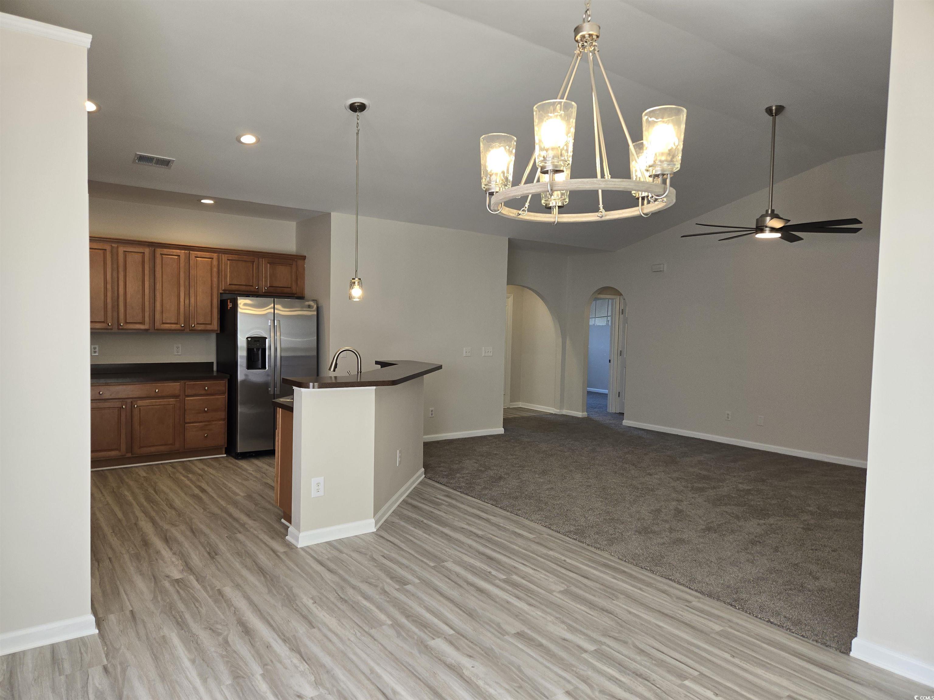 129 Powder Springs Loop Myrtle Beach, SC 29588 - Photo 4 of 23 Kitchen with dark countertops, hanging light fixtures, a chandelier, stainless steel refrigerator with ice dispenser, and arched walkways