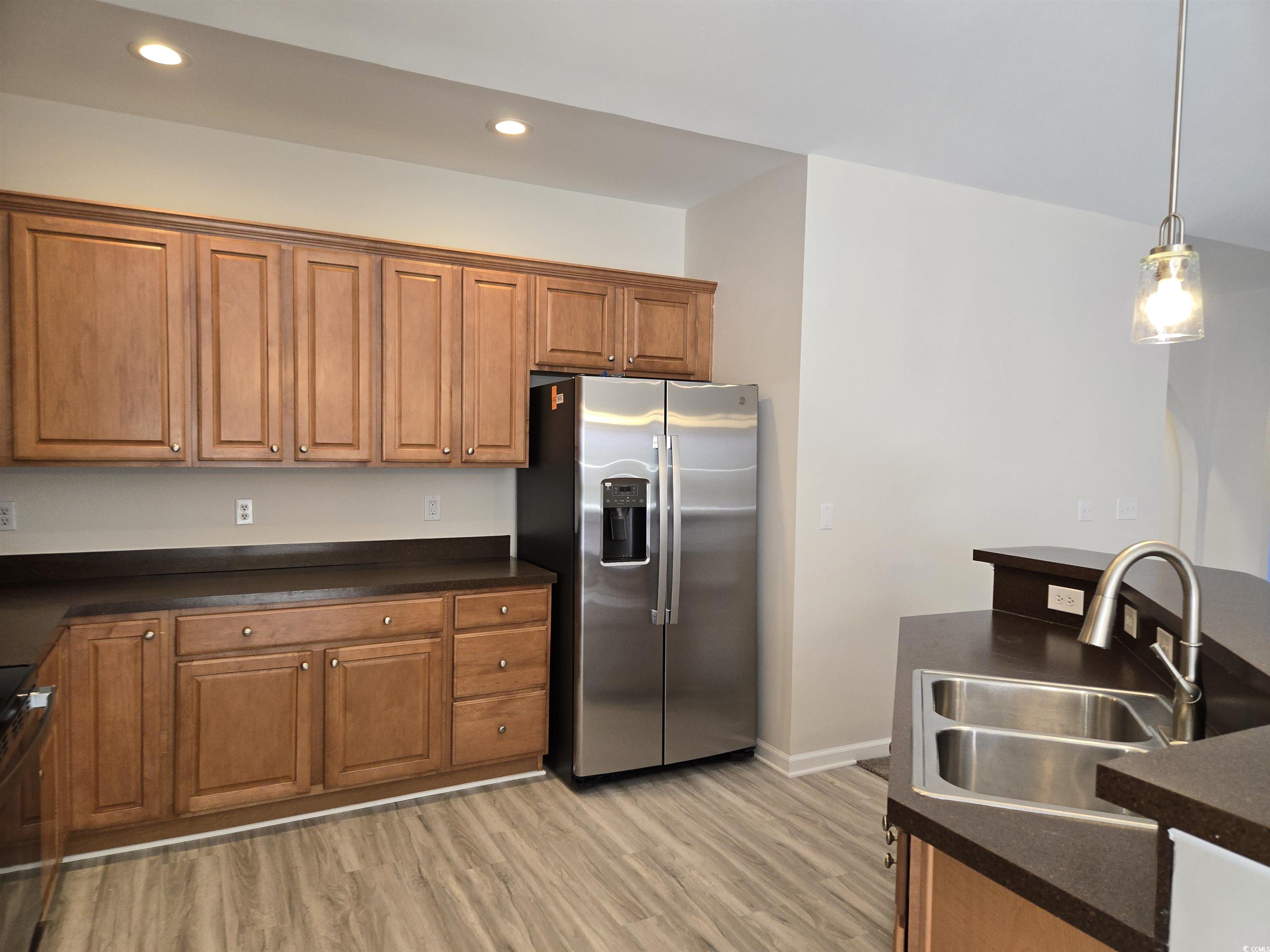 129 Powder Springs Loop Myrtle Beach, SC 29588 - Photo 6 of 23 Kitchen featuring dark countertops, stainless steel refrigerator with ice dispenser, brown cabinetry, pendant lighting, and range