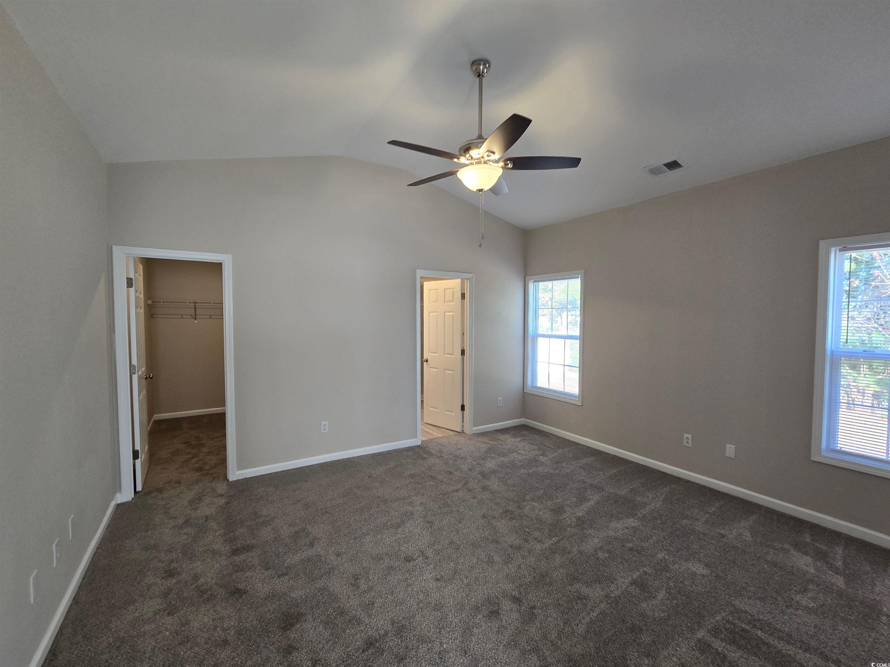 129 Powder Springs Loop Myrtle Beach, SC 29588 - Photo 7 of 23 Unfurnished master bedroom featuring a spacious closet, vaulted ceiling, dark carpet, and ceiling fan