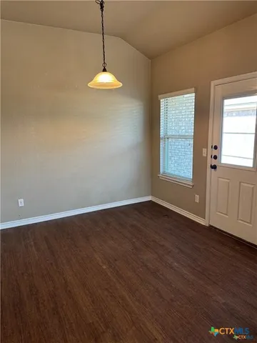 an empty room with wooden floor cabinet and windows