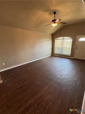 an empty room with wooden floor chandelier and windows