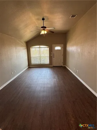 a view of a big room with wooden floor a chandelier fan and windows