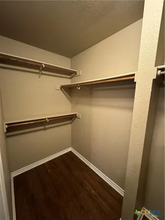 a view of an empty room with a ceiling fan and wooden floor