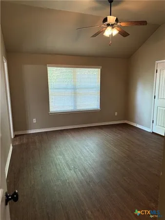 a view of an empty room with a window and wooden floor