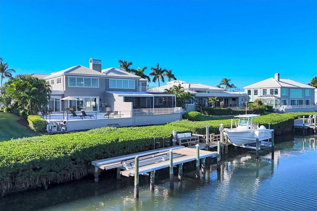 3540 Mistletoe Lane Longboat Key, FL 34228 - Photo 3 of 80 a wooden bench sitting in backside of a house with pool lawn chairs and a yard