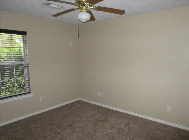 an empty room with a window and a fan