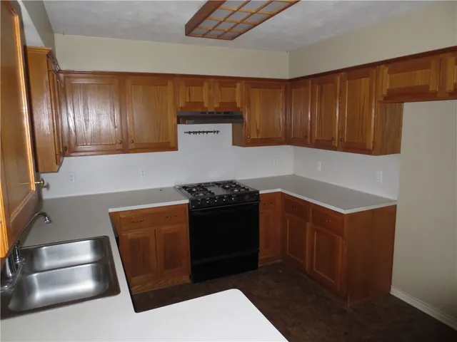 a kitchen with stainless steel appliances granite countertop a stove a refrigerator and a sink with wooden cabinets