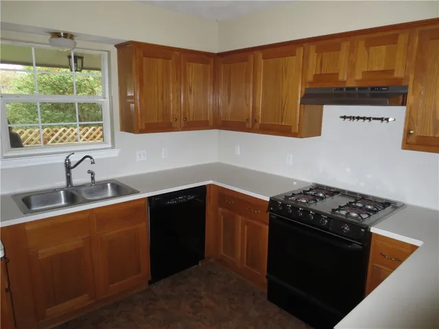a kitchen with granite countertop stainless steel appliances a stove a sink dishwasher and cabinets with wooden floor