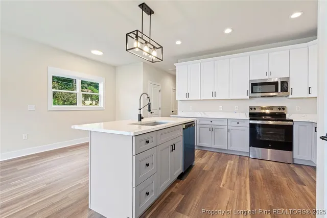 a kitchen with a center island wooden floor and stainless steel appliances