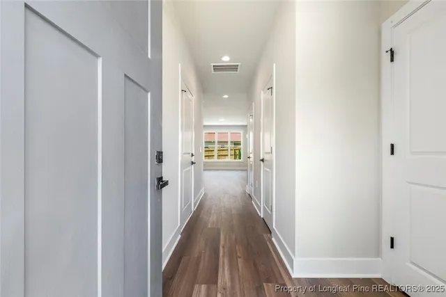 a view of a hallway with wooden floor and a bathroom