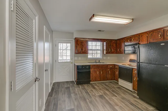 a kitchen with stainless steel appliances granite countertop a refrigerator a sink dishwasher a stove and white countertops with wooden floor