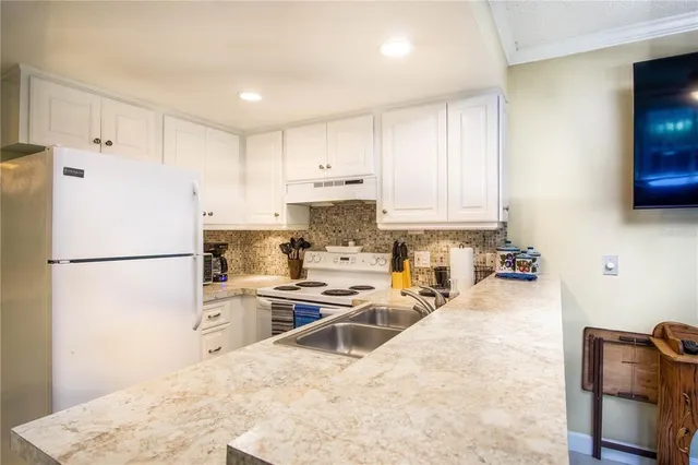 a kitchen with refrigerator a stove a sink a counter top space and cabinets