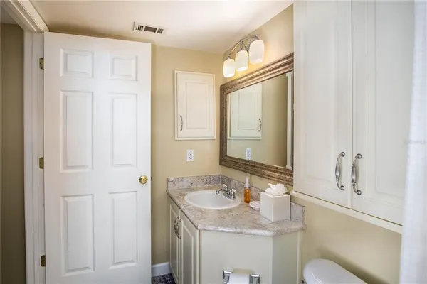 a bathroom with a sink vanity granite tub and a mirror