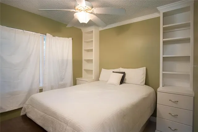 a large bed sitting in a bedroom next to a window and a chandelier