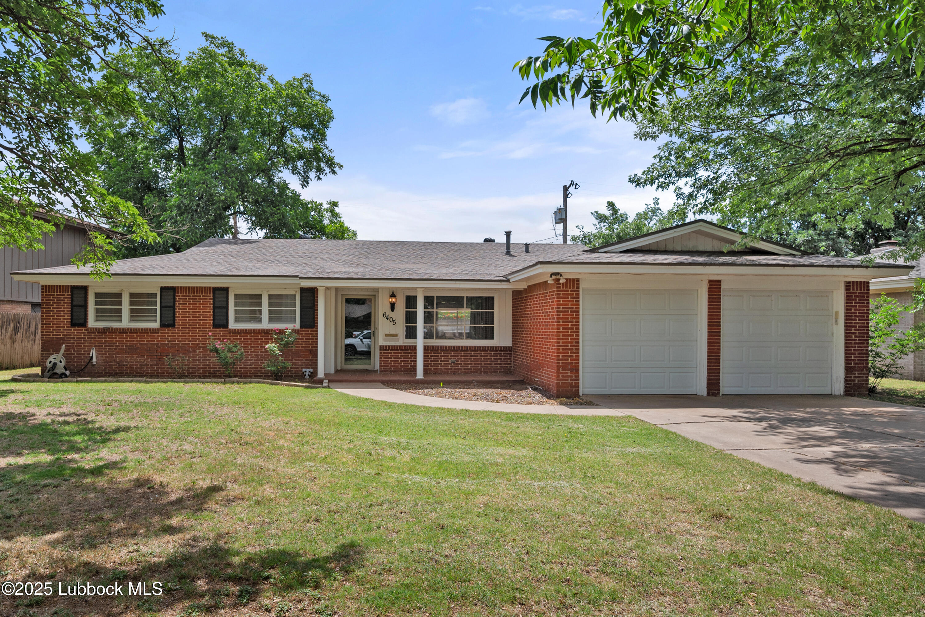 a front view of a house with a garden and trees