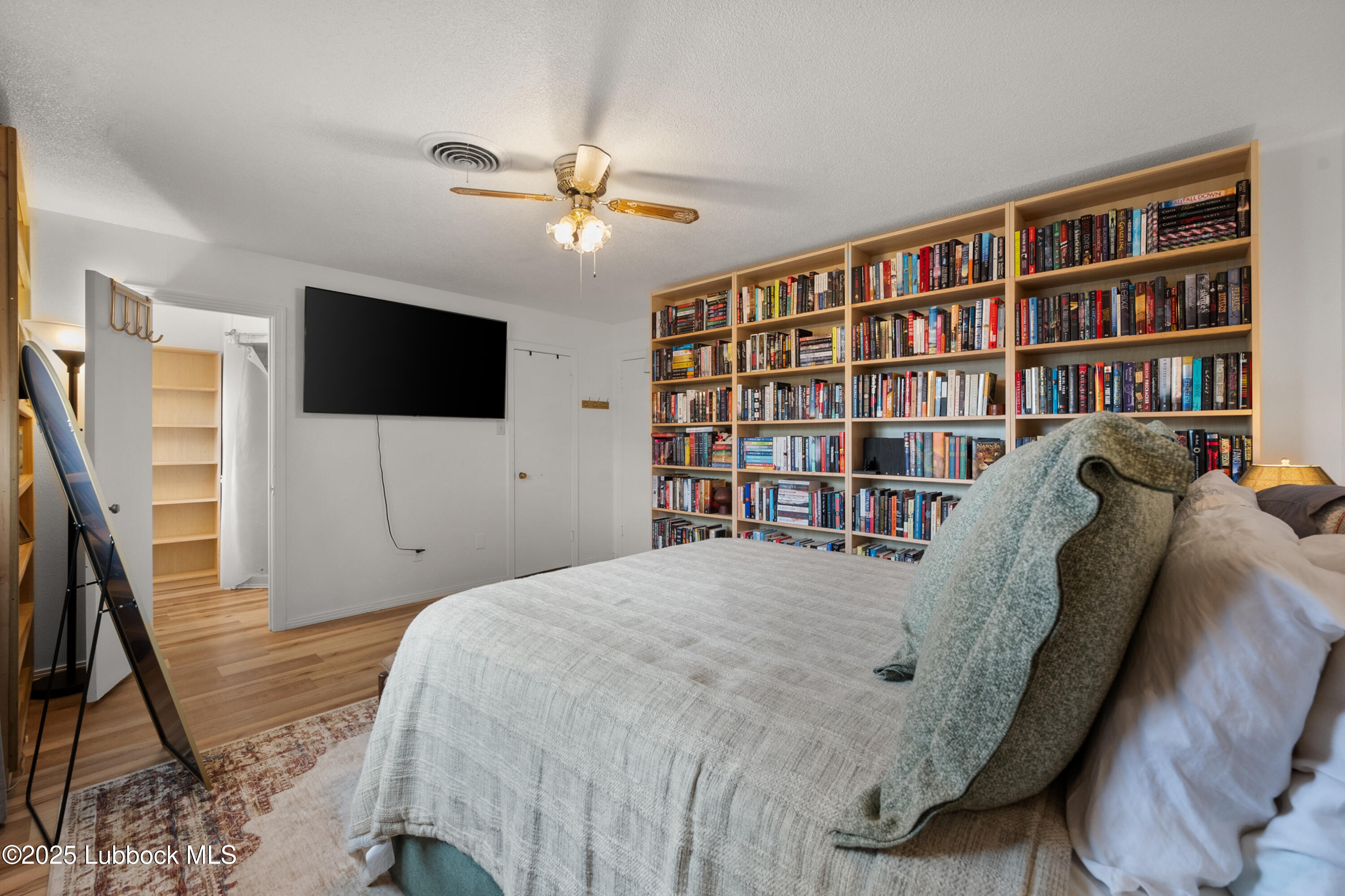 6405 Joliet Avenue Lubbock, TX 79413 - Photo 21 of 30 a bedroom with a bed a flat screen tv and a book shelf