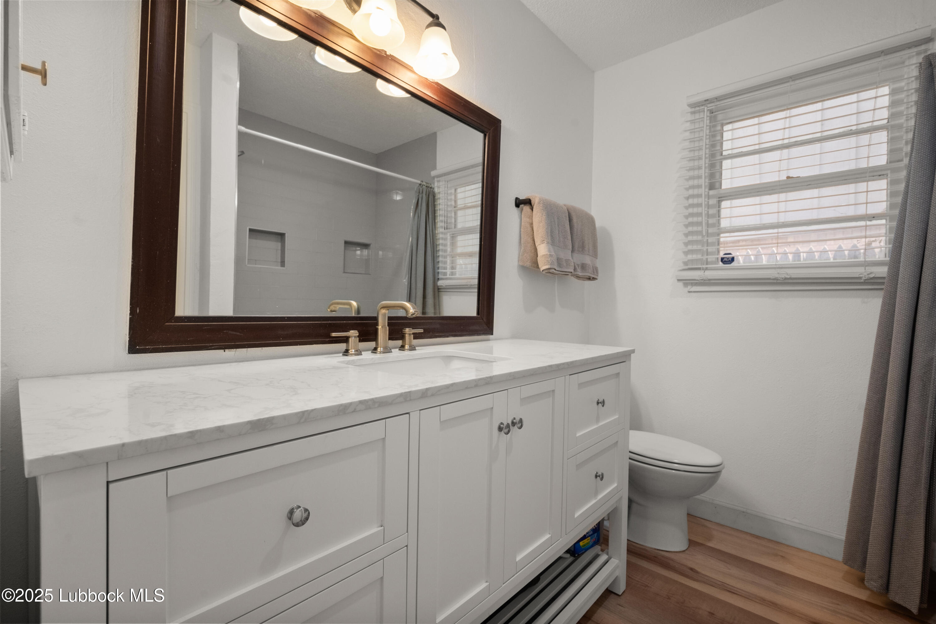 6405 Joliet Avenue Lubbock, TX 79413 - Photo 27 of 30 a bathroom with a granite countertop toilet sink and mirror