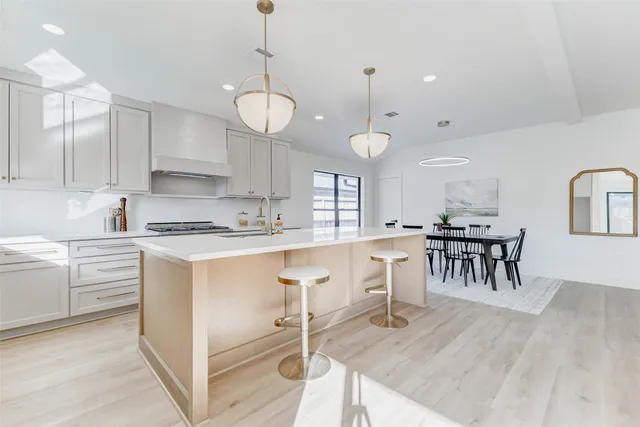 a large white kitchen with lots of counter space dining table and stainless steel appliances