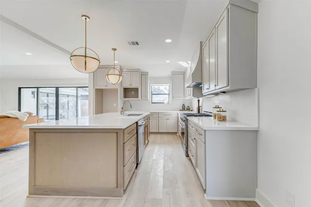 a kitchen with stainless steel appliances granite countertop a sink a stove and a wooden floors