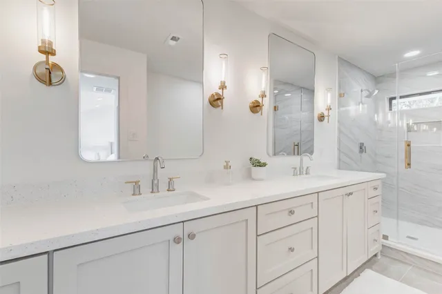 a bathroom with a double vanity sink mirror and shower