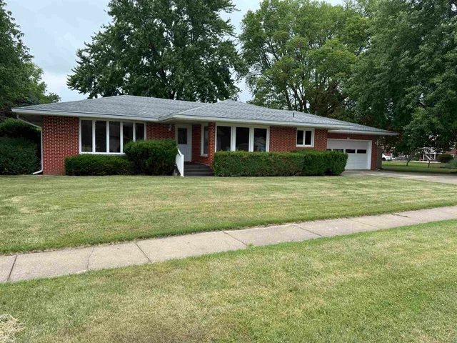 a front view of a house with a yard and trees